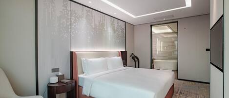 Una habitación de hotel moderna con una cama grande, una mesita de noche, una silla y un espejo amplio.