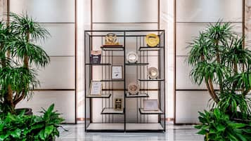 A display case with awards and plaques, surrounded by potted plants.
