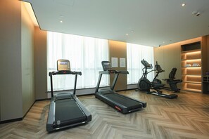 Un gimnasio con cintas de correr, elípticas y una bicicleta estática.