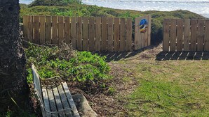 A wooden fence, a bench, and a view of the ocean. - The Gin Trap (Pukehina)