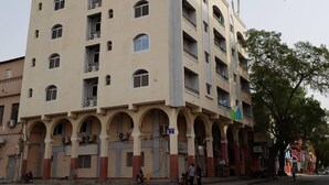 Ein mehrgeschossiges Gebäude mit beiger Fassade, mehreren Balkonen und einer Reihe von Bögen im Erdgeschoss.