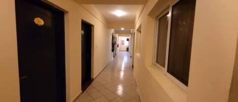 A hallway with doors, a tiled floor, and a ceiling light.
