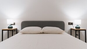 Un lit bien fait, avec deux oreillers et deux tables de chevet, chacune équipée d’une lampe.