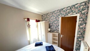 A bedroom with a bed, a wardrobe, a radiator, and a door. - 2 Bedroom Holiday Apartment - Flat 18 (Skegness)