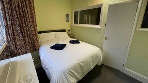 Hotellihuone, jossa on sänky, työpöytä, ikkuna ja ovi.