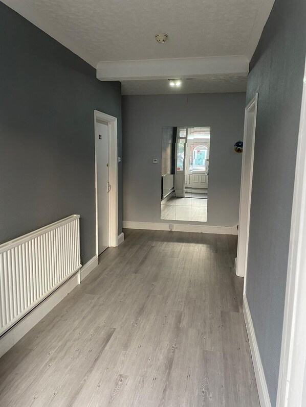 Un couloir aux murs gris, aux boiseries blanches et au plancher en bois.