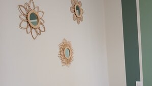 A bedroom with a bed, a green door, and three wall-mounted mirrors.