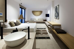A modern hotel room with a large bed, a white bathtub, a wooden bench, and a large window. - 115m2 pool, daily cleaning, sauna, near beaches! (Chania)