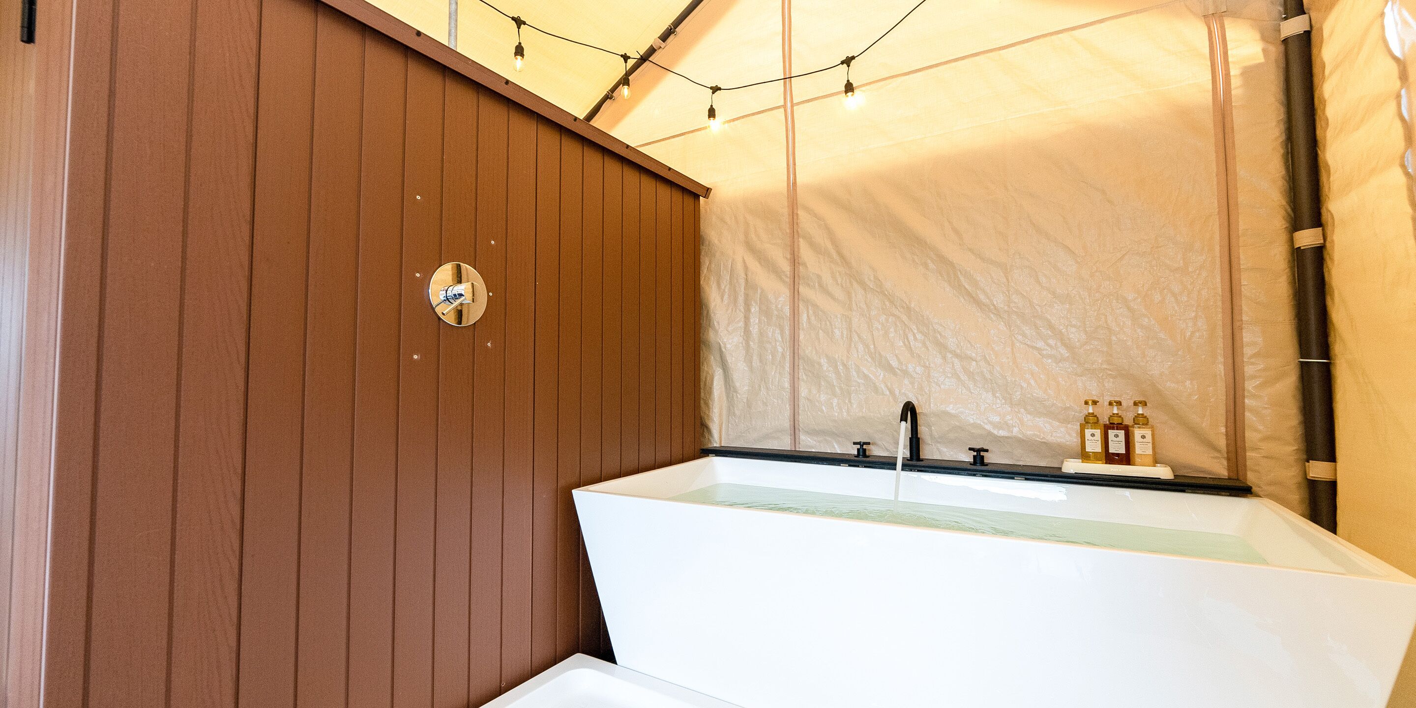 A bathroom with a wooden panel wall, a white sink with a mirror, and a towel rack.