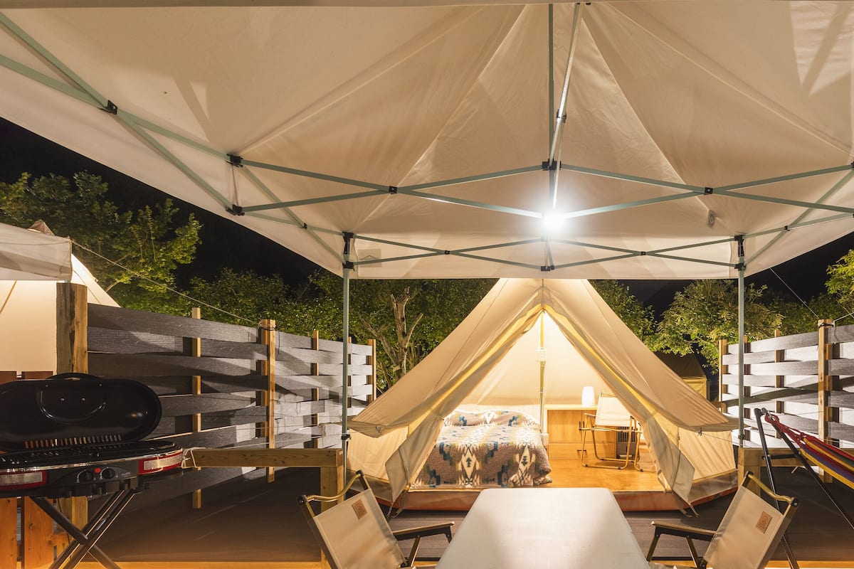 Een tentaccomodatie met een barbecue en zithoek.