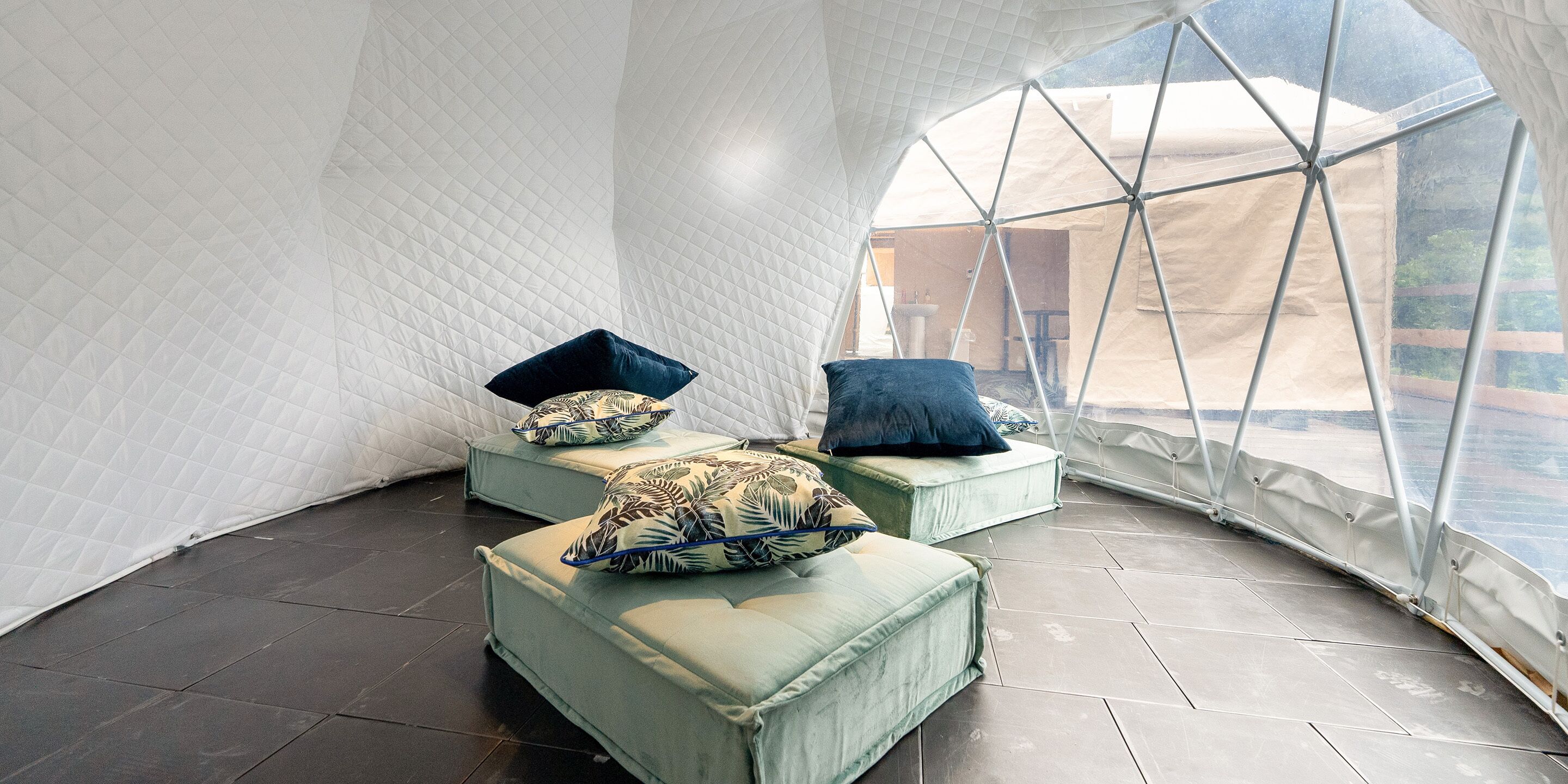 Uma estrutura em forma de tenda com design geométrico, apresentando duas áreas de estar acolchoadas com almofadas estampadas.
