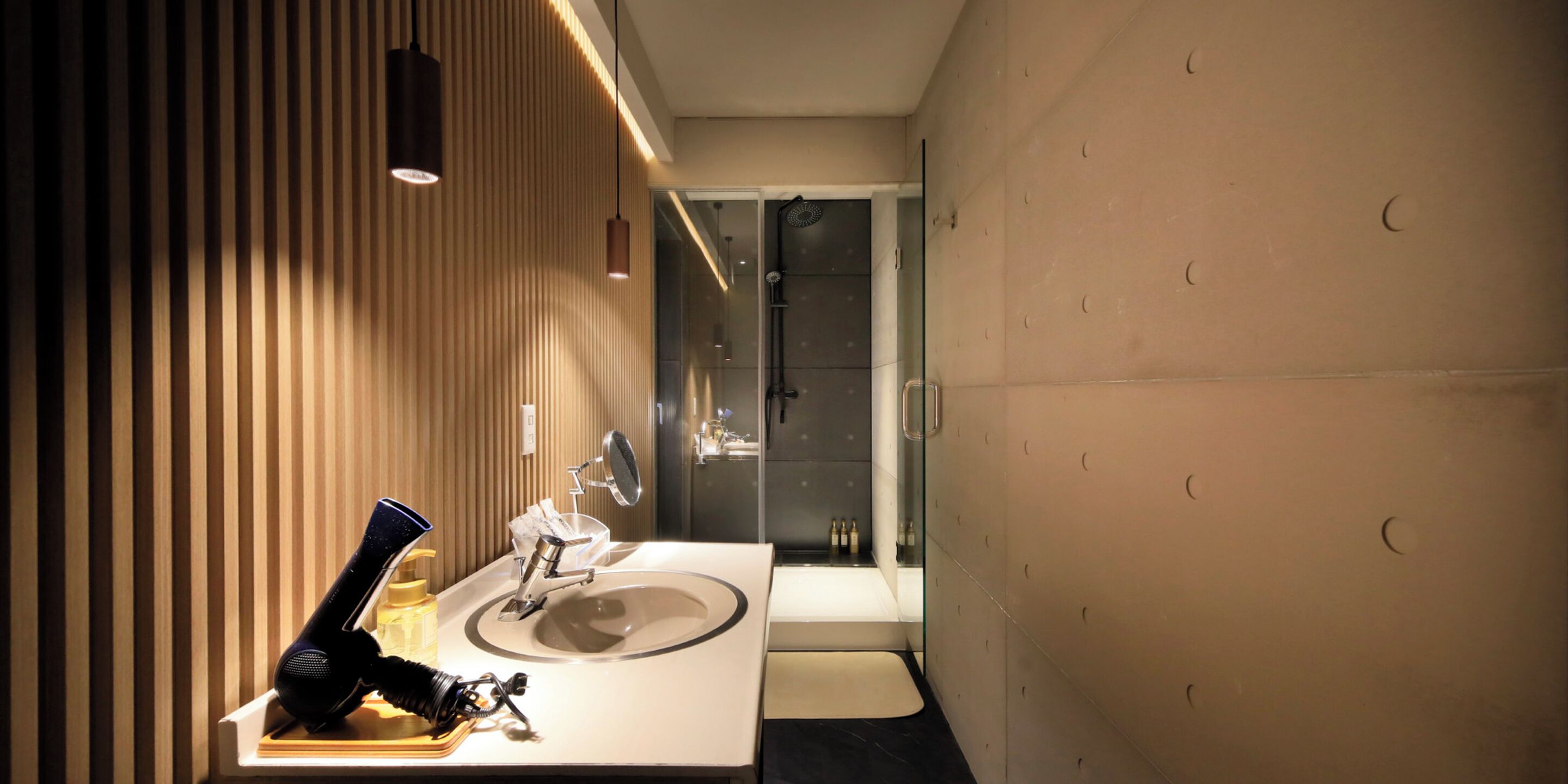 Une salle de bain moderne avec un grand lavabo, un miroir et un espace douche.