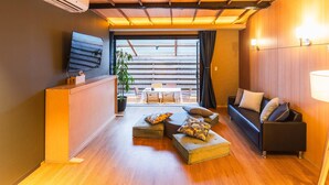 Un salon moderne avec un plafond en bois, un téléviseur à écran plat, un canapé, une table basse et un coin repas comprenant une table et des chaises.