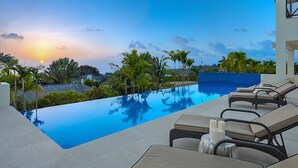 A poolside area with lounge chairs and a view of the sunset over the ocean. - Infinity House | Ultra-Luxury Sea View Estate in Calijanda, Barbados (Holetown)