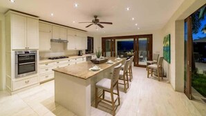 A modern kitchen with a central island, built-in oven, and a ceiling fan. - Infinity House | Ultra-Luxury Sea View Estate in Calijanda, Barbados (Holetown)