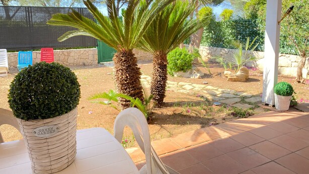 A patio area with a white table, a potted plant, and a stone wall.