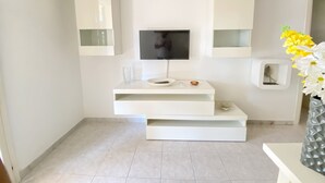 A modern bathroom with a built-in TV, white cabinetry, and a vase of flowers.