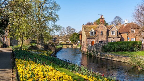 A canal with a brick building and a stone bridge in the background. - Stylish, City Centre 3-bed House With Parking (Canterbury)