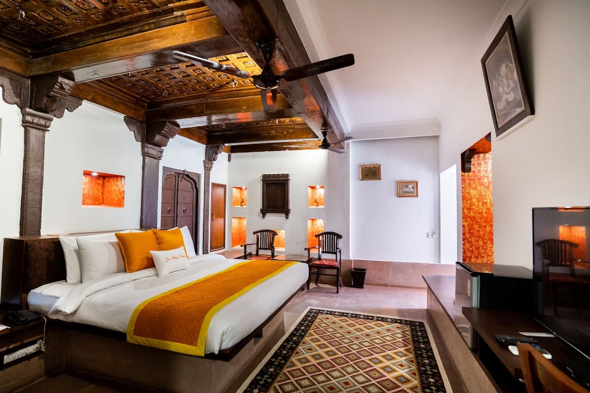 Quarto de hotel com cama, televisão, escrivaninha e cadeira.