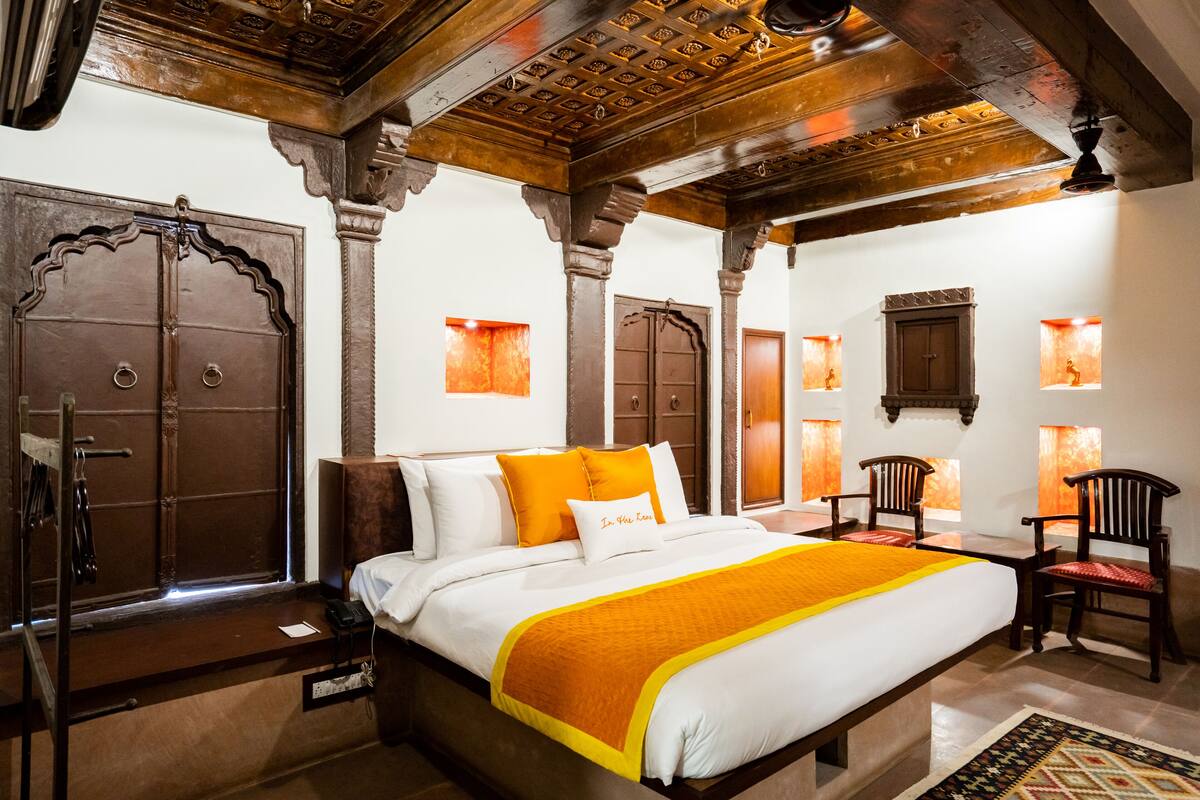 Quarto tradicional com cama grande, mobiliário de madeira e portas decoradas.