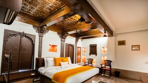 Een klassieke kamer met een groot bed, houten plafond en een versierde deur.