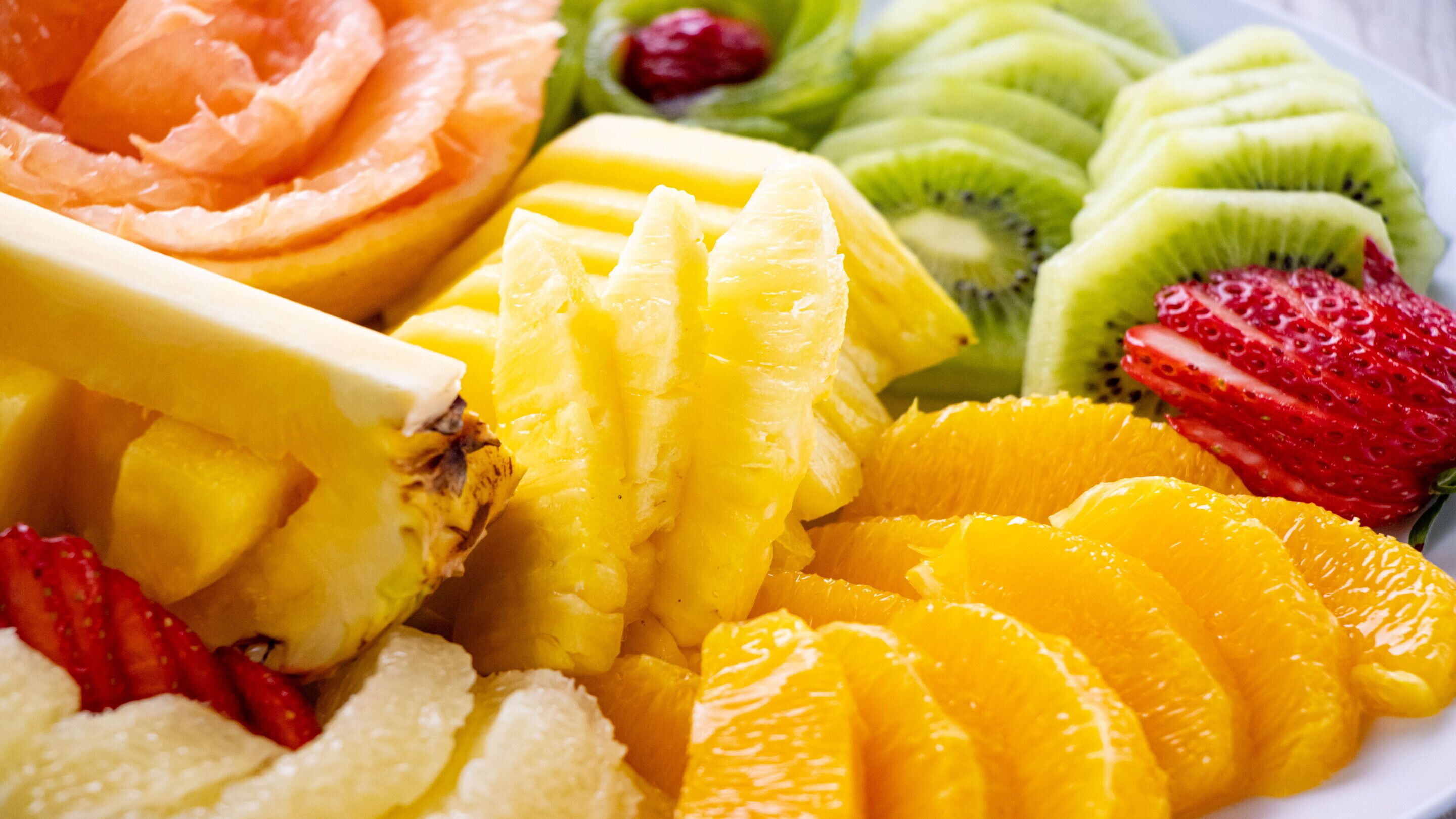 A plate of assorted fruits including sliced oranges, kiwi, strawberries, and pineapple.