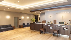 Un espace d’enregistrement et de départ en libre-service comprenant un comptoir d’accueil, un coin salon et un plancher en bois.
