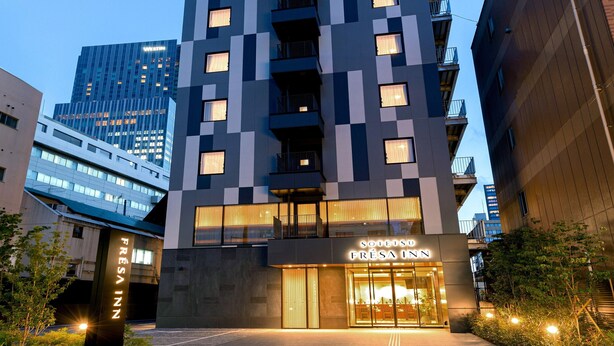 Un hôtel moderne à la façade à carreaux, doté de grandes fenêtres et d’une entrée bien visible.