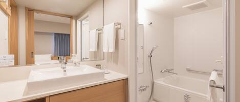 Un baño moderno con lavamanos, espejo y ducha.