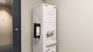 A wall-mounted water dispenser with a push button and a glass.