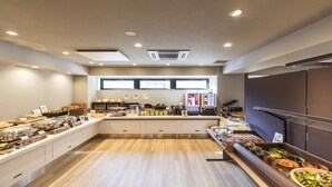 Un espace buffet avec différents postes de service pour les aliments, une machine à café et une fenêtre laissant entrer la lumière naturelle.