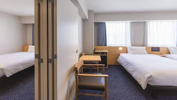 A hotel room with two beds, a desk, and a chair.