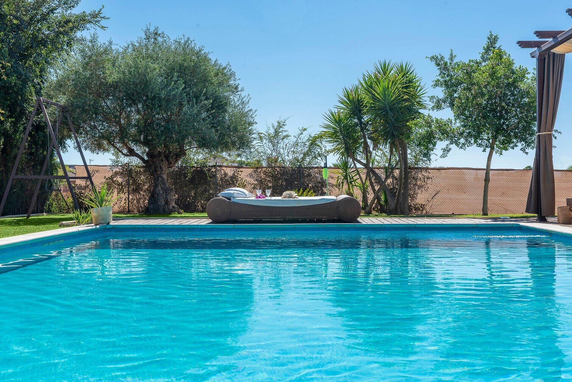 A swimming pool with a lounge chair and a small table with a drink.