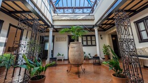 A spacious courtyard with a large central pot, potted plants, and a glass ceiling. - Holiday Home "Casa Rural La Teja" with Pool, Garden and Wi-Fi (Marchena)