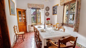 Una sala da pranzo con un tavolo imbandito per quattro persone, un mobiletto in legno e un lampadario.