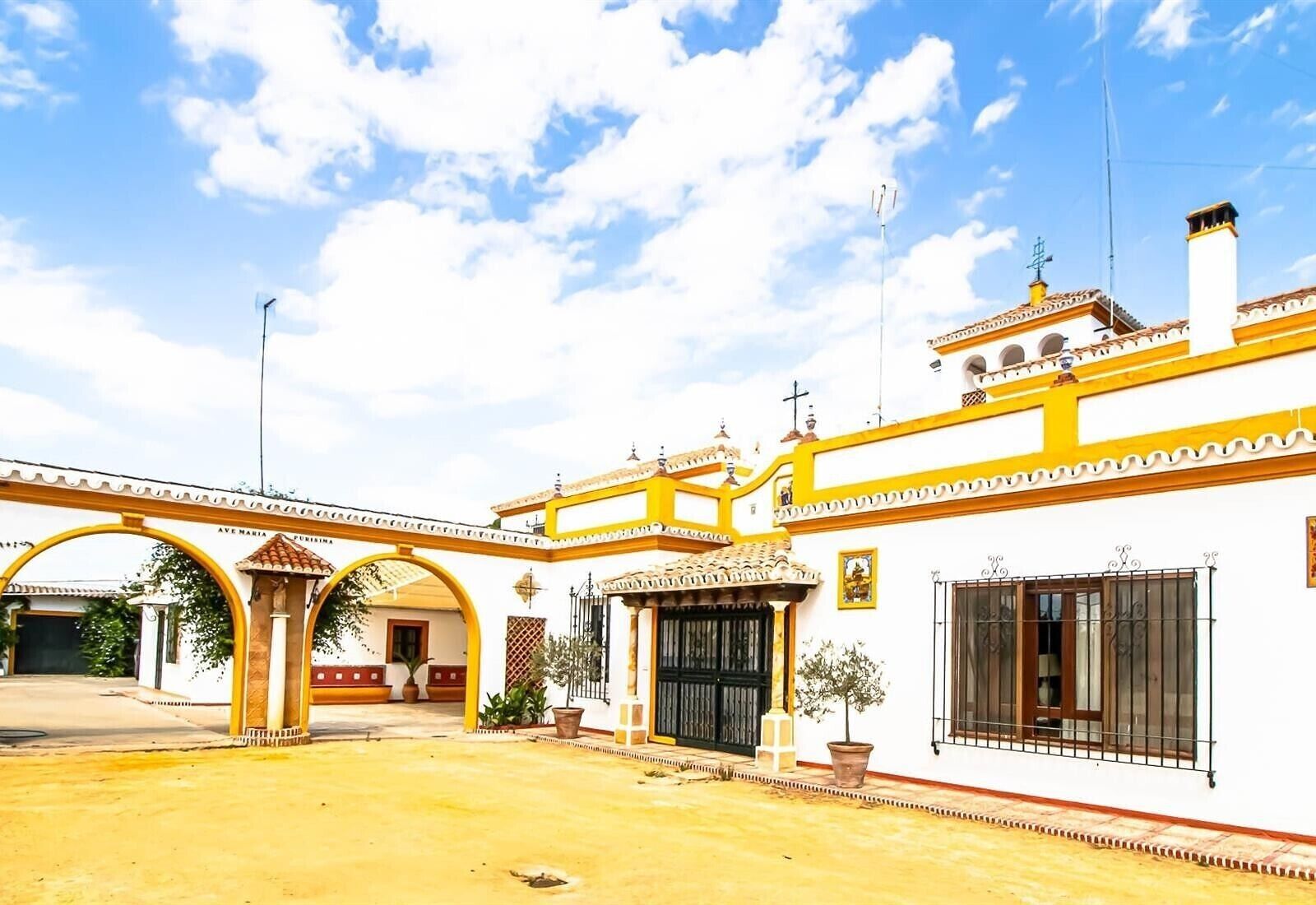 Edifici amb façana groga i blanca, múltiples arcs i entrada amb reixa.