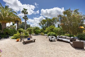 An outdoor patio area with a gravel surface, a wooden bench, a sofa, and various potted plants. - Quinta das Achadas - Jasmine in Lagos with Shared Pool, Nature & Breakfast (Lagos)
