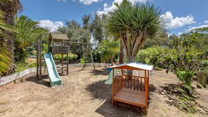 A playground with a slide, swings, and a wooden bench. - Quinta das Achadas - Jasmine in Lagos with Shared Pool, Nature & Breakfast (Lagos)
