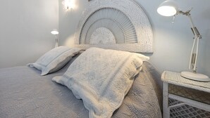 A bed with a textured blanket, a white headboard, and a bedside lamp. - Quinta das Achadas - Jasmine in Lagos with Shared Pool, Nature & Breakfast (Lagos)