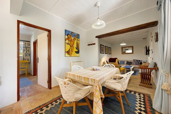 A dining area with a table set for four, surrounded by chairs, a ceiling fan, and a painting on the wall.