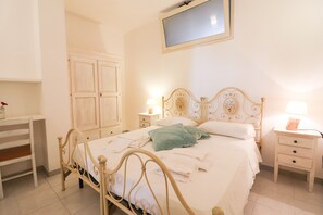 Une chambre à coucher avec un lit, des tables de chevet, une commode et un téléviseur fixé au mur.