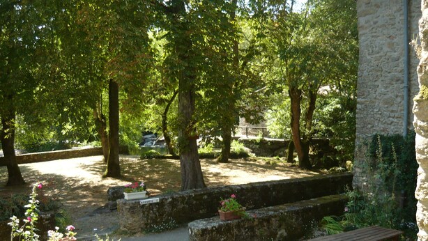 A courtyard with a stone wall, a picnic table, and potted plants. - Gîte "Manoir" with garden by the river, near Clisson (Gétigné)