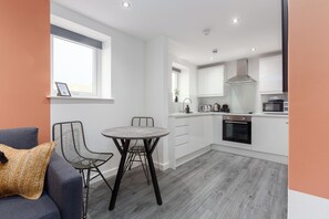 A modern kitchen with white cabinets, a built-in oven, and a microwave.