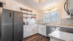 A modern kitchen with stainless steel appliances, white cabinetry, and a window providing a view of the outdoors.