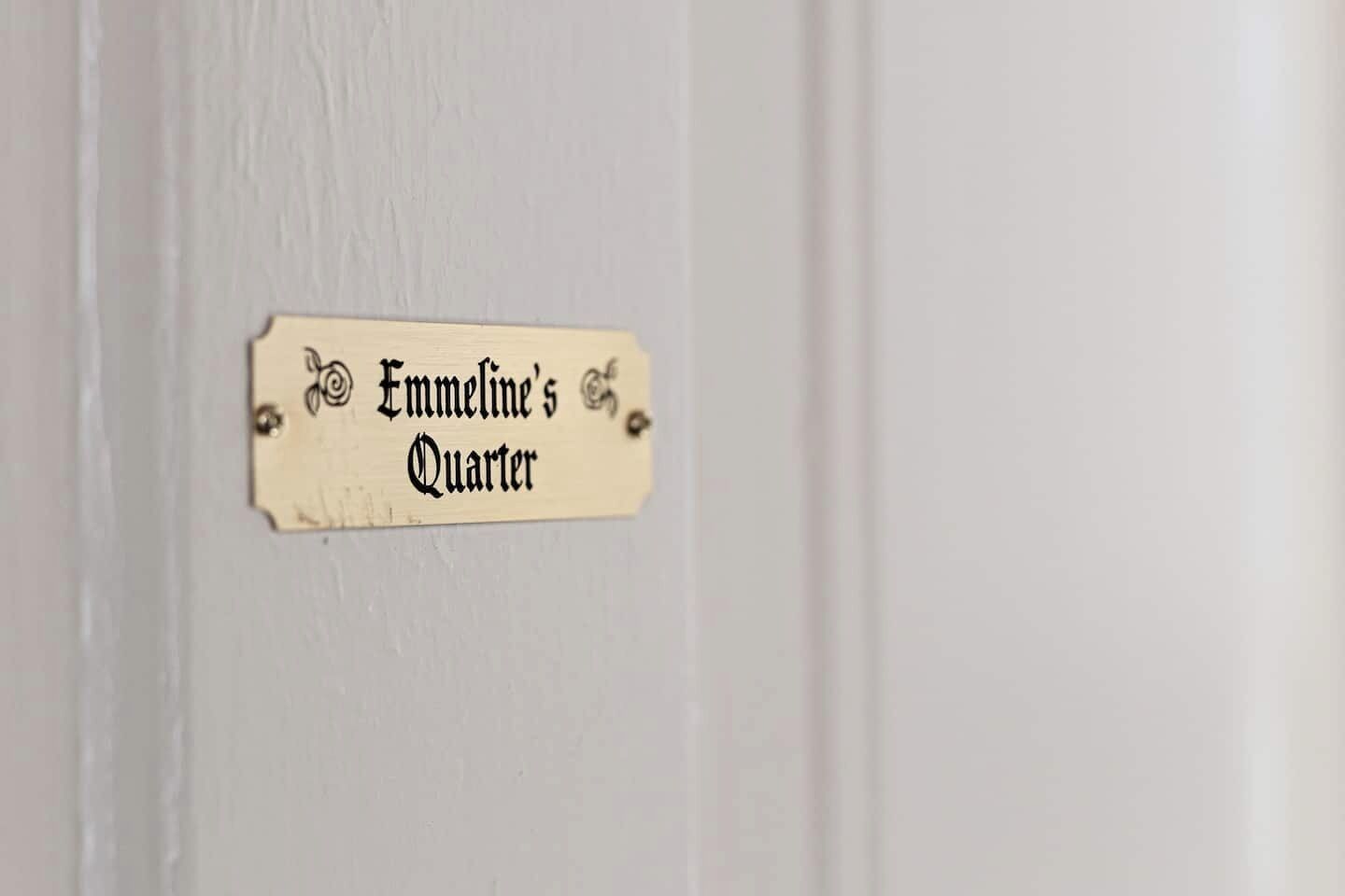 Ein Schild mit dem Text 'Emmeline's Quarter' an einer weißen Tür.