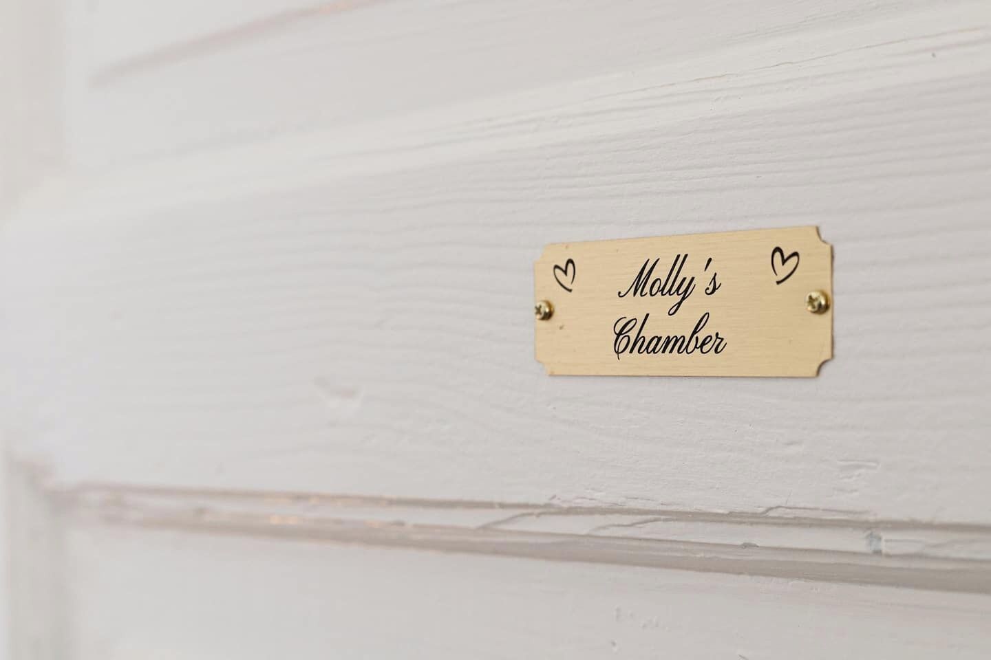 A wooden door with a brass nameplate that reads 'Molly's Chamber.'