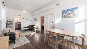 A spacious living area with a wooden dining table, a sofa, and a kitchen in the background.