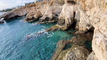 A coastal landscape with rocky cliffs and clear turquoise water.