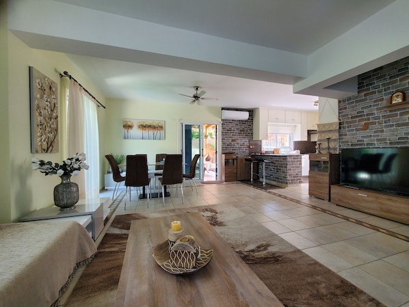 A spacious living area with a dining table, chairs, a coffee table with decorative items, a fireplace, and a TV. - Villa - Sleeps 6, Free Parking & Heated Pool (Paralimni)