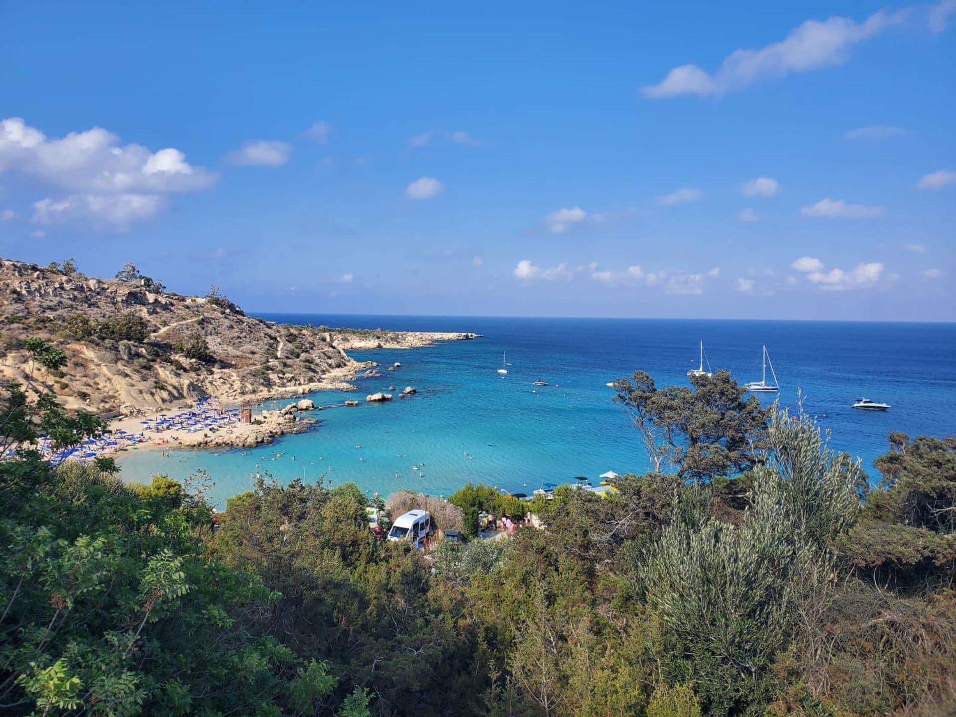 Eine Küstenlandschaft mit Strand, felsigem Gelände und klarem, blauem Meer.